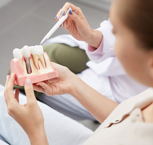 Dentist showing model dental implant to patient