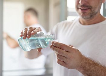 Smiling patient pouring mouthwash in cap