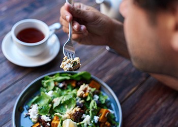 Man enjoying salad and tea at a wooden table