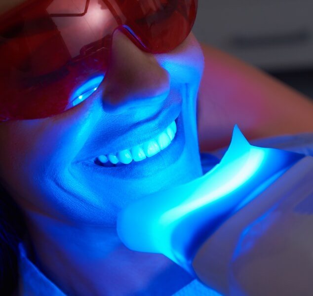 Woman in dental chair receiving professional teeth whitening