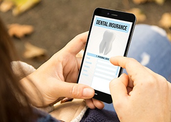 Patient looking at dental insurance form on phone outside