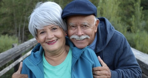 Senior man and woman hugging on bridge in woods
